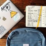 computer-with-stickers-backpack-and-open-notebook-with-notes-and-graphs