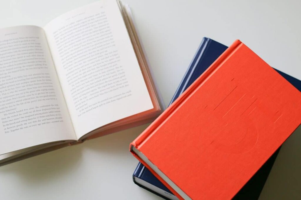 Three books on a table, one laid open