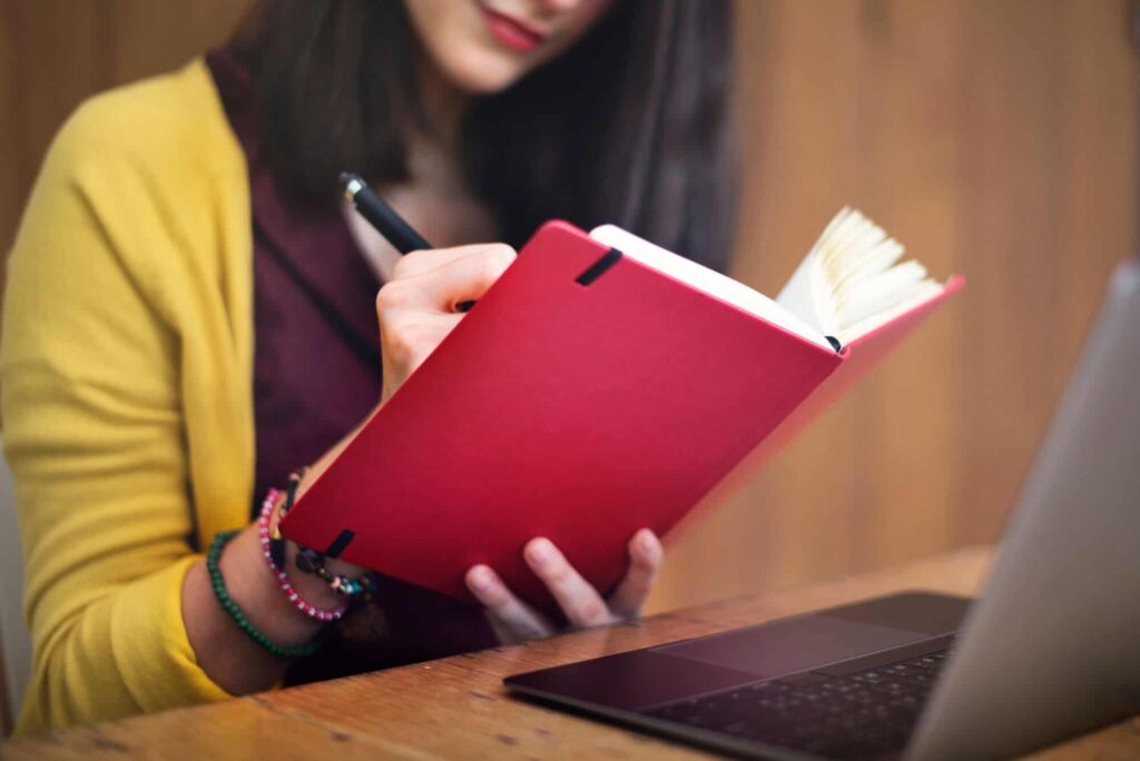 Woman writing in red notebook
