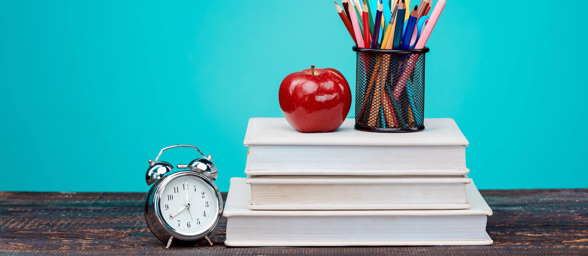 Books, pencils, apple, and clock