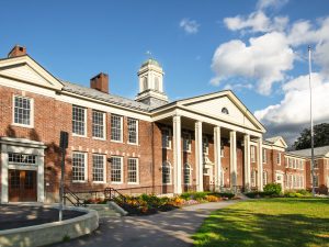 Red-brick school with white columns and a cupola.