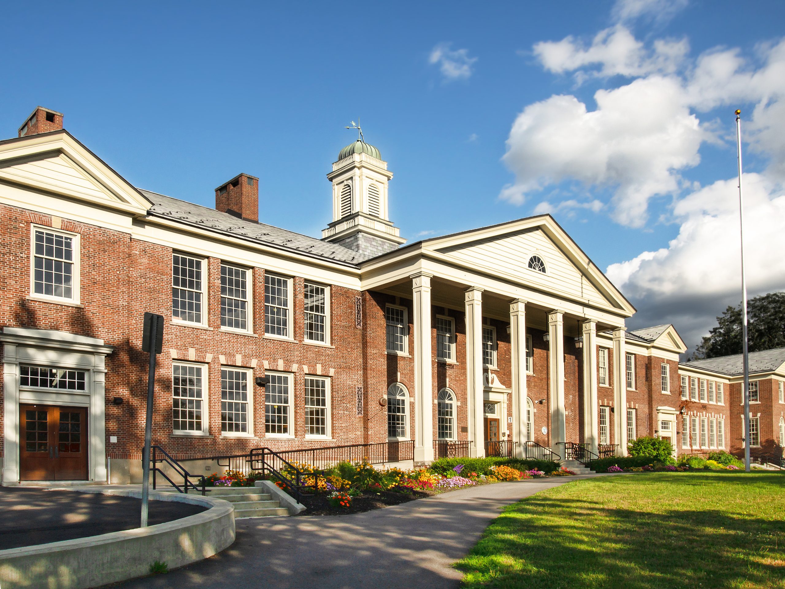 Red-brick school with white columns and a cupola.