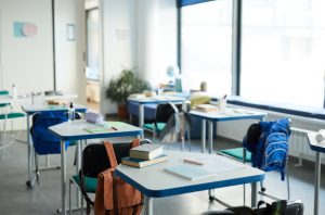 Bright classroom with desks, backpacks, and school supplies.